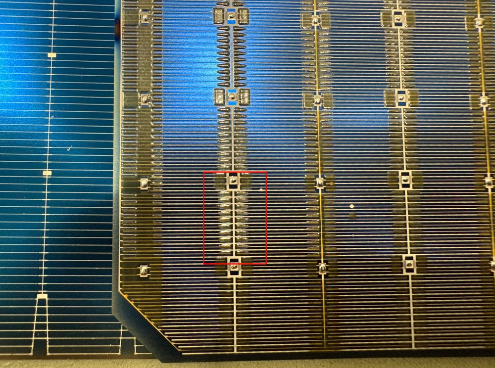 Close up of a BC solar cell backside showing interleaved positive and negative electrode zones with an insulating region highlighted